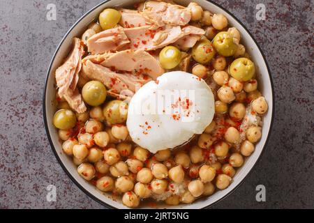 Kichererbsen in Brühe, serviert mit Thunfisch aus der Dose, Oliven und pochiertem Ei in einer Schüssel auf dem Tisch. Horizontale Draufsicht von oben Stockfoto