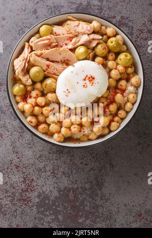 Tunesisches Gericht Lablabi oder Lablebi auf Basis von Kichererbsen in einer dünnen Knoblauch- und Kreuzkümmel-Brühe, garniert mit einem pochierten Ei und Thunfisch-Closeup in der Schüssel auf der Ta Stockfoto
