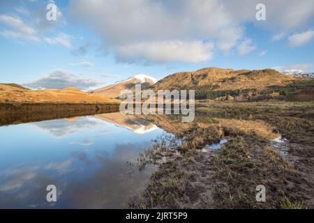 Gebiet von Crianlarich, Schottland. Malerischer Blick in die Dämmerung auf den Fluss Fillan mit einem schneebedeckten Ben More im Hintergrund. Stockfoto