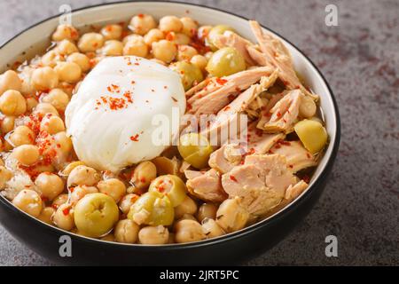 Kichererbsen in Brühe, serviert mit Thunfisch aus der Dose, Oliven und pochiertem Ei in einer Schüssel auf dem Tisch. Horizontal Stockfoto