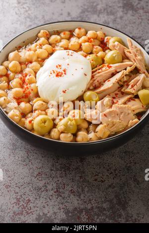 Tunesisches Gericht Lablabi oder Lablebi auf Basis von Kichererbsen in einer dünnen Knoblauch- und Kreuzkümmel-Brühe, garniert mit einem pochierten Ei und Thunfisch-Closeup in der Schüssel auf der Ta Stockfoto