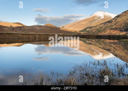 Gebiet von Crianlarich, Schottland. Malerischer Blick in die Dämmerung auf den Fluss Fillan mit einem schneebedeckten Ben More im Hintergrund. Stockfoto