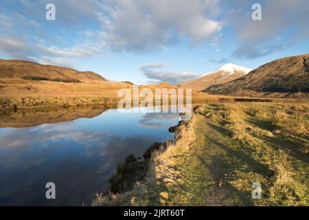 Gebiet von Crianlarich, Schottland. Malerischer Blick in die Dämmerung auf den Fluss Fillan mit einem schneebedeckten Ben More im Hintergrund. Stockfoto