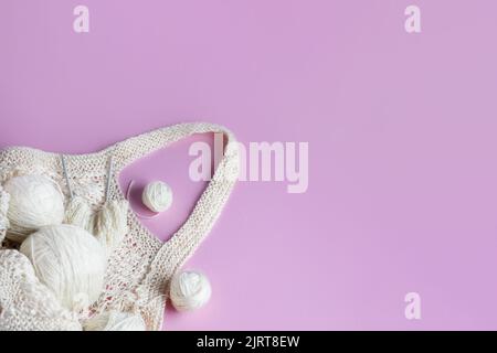 Weiße Kugeln aus Faden in einem Korb auf einem rosa Hintergrund, Hobby Stockfoto