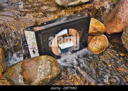 Kleines metallisches Wasserrad im Bach Stockfoto