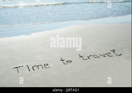 Konzept oder konzeptionelle Zeit zu reisen handgeschriebener Text im Sand an einem Strand mit Wellen auf einer exotischen Insel für Abenteuer, Sommer, Meer, Reisen Stockfoto
