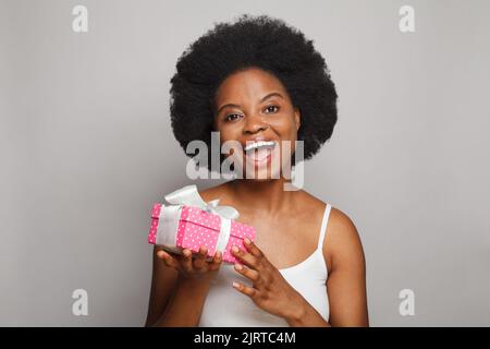 Happy nice aufgeregt Frau Brünette Modell hält rosa Geschenk Geschenkbox mit weißem Seidenband auf weißem Hintergrund Stockfoto