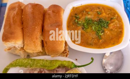 PAV Bhaji Fast-Food-Gericht aus Indien. Besteht aus einem dicken Gemüsearschrot, serviert mit einem weichen Brötchen, serviert auf einem Teller. Stockfoto