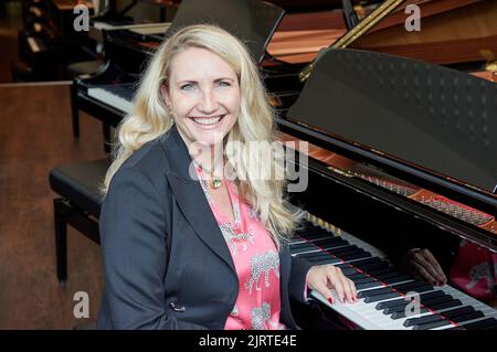 Hamburg, Deutschland. 25. August 2022. Yvonne Trübger, Inhaberin, sitzt während einer Fotosession am Flügel, um das 150.-jährige Jubiläum des Pianohaus Trübger zu feiern. Das Klavierhaus ist eines der letzten Klavierhäuser, das nicht nur eine Marke repräsentiert. (To dpa 'Pianohaus Trübger verschenkt 15 Klaviere zum 150.-jährigen Jubiläum') Quelle: Georg Wendt/dpa/Alamy Live News Stockfoto