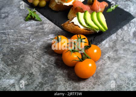 Leckere Snacks, Sandwiches, Crostini, Canape, Antipasti mit Lachs Avocado, Tomaten, Frischkäse, Mozzarella für Party, Geburtstag. Das Konzept der gesunden Ernährung und der mediterranen Küche. Stockfoto