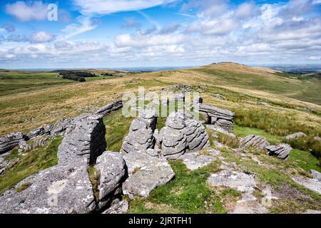 Granitfelsen am Oke Tor und Blick auf den Belstone Ridge in Richtung Higher Tor und Belstone Tor. Dartmoor-Nationalpark, Devon, Großbritannien. Stockfoto
