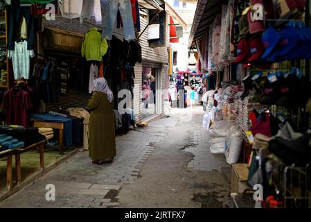 Alte Frau im Hijab, die auf dem traditionellen türkischen Markt für Kleidung in Trabzon steht Stockfoto