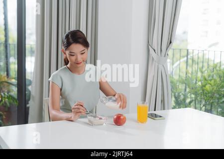 Frau, Gießen Milch auf Platte mit Getreide Musselin in Küche Stockfoto