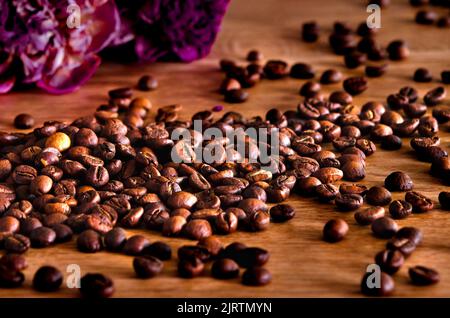 Kaffee. Geröstete Kaffeebohnen auf einem Holztisch verstreut Stockfoto
