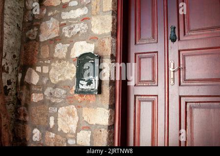 Vordertür und Metallmailbox eines alten Steinhauses. Rote Straßentür Aus Der Nähe. Marmaris, Türkei - 8. September 2022 Stockfoto