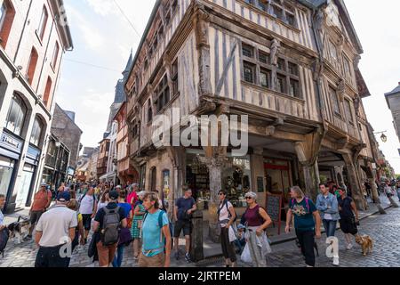 Touristenmassen, die eine Einkaufsstraße in der Innenstadt der mittelalterlichen Stadt Dinan, Bretagne, Frankreich, besuchen Stockfoto