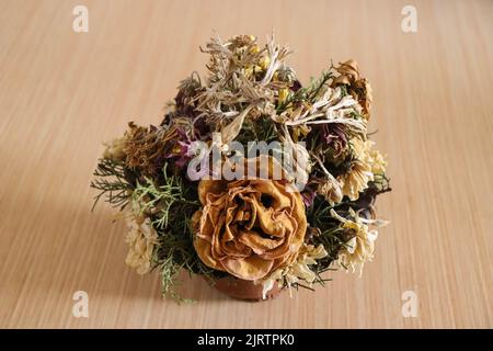 Eine Nahaufnahme eines Straußes von immerwährenden Blumen auf einem Holztisch Stockfoto