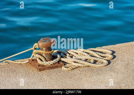 Nahaufnahme eines rostigen Pollers mit Seilen oder Falschhändlern am Kai des Hafens. Golf von La Spezia, Ligurien, Italien, Europa. Stockfoto