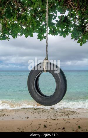 Lokale Fidschi's bauten eine selbstgemachte Reifenschaukel an einem abgelegenen Strand mit einer fantastischen Aussicht. Stockfoto