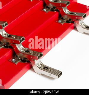 Rote Fronten für eine Kommode mit Metallscharnieren liegen auf weißem Hintergrund. Stockfoto