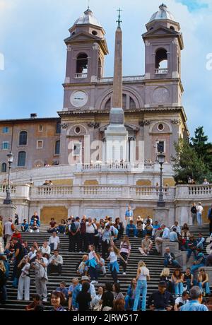 Rom Italien Besucher sitzen auf der Spanischen Treppe mit Trinita Dei Monti Kirche und Sallustiano Obelisk oben Stockfoto