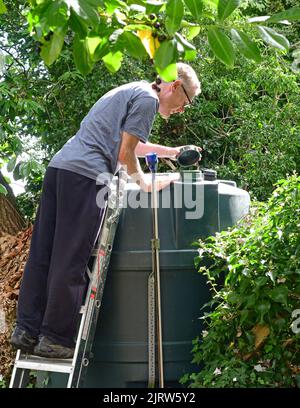 Mann, der den Füllstand des inländischen Heizöl-Tanks im Garten vereinigtes Königreich überprüft Stockfoto