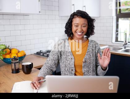 Eine junge, multiethnische Frau begrüßt ihre Kollegen, die von der Küche aus arbeiten Stockfoto