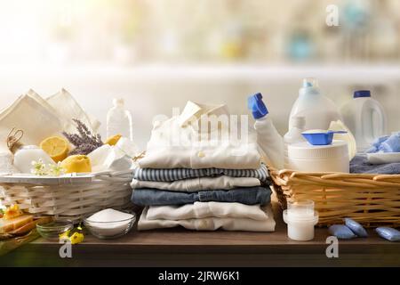 Detailvergleich von ökologischen Wäschereireinigungsprodukten auf Holztisch und Chemikalien in der Hauswäsche. Vorderansicht. Horizontale Zusammensetzung. Stockfoto