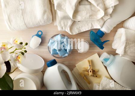 Detail von chemischen Waschmitteln auf Holztisch für weiße Kleidung mit Hemden und Handtüchern. Draufsicht. Horizontale Zusammensetzung. Stockfoto