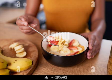 Eine Nahaufnahme einer jungen Frau, die zum Frühstück eine Schale Cornflakes mit Obst isst Stockfoto
