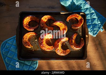 Ein Stillleben eines gerösteten Kürbisses im Sonnenlicht auf dem Tisch Stockfoto