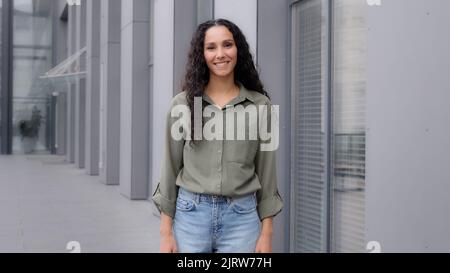 Rückansicht von hinten Frau mit dunkler Gesundheit lockiges langes Haar Brünette Frau Geschäftsfrau Spaziergänger zu Fuß in der Stadt in der Nähe der Innenstadt Firmengebäude Stockfoto