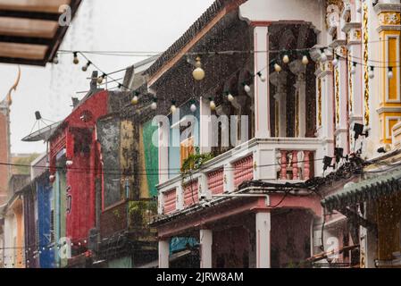 Phuket, Thailand - 2022. Juli: Monsun-Regen auf den farbenfrohen Häusern in der Soi Rommani Street in der Altstadt von Phuket. Stockfoto