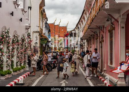 Phuket, Thailand - Juli 2022: Menschen, die entlang der Soi Rommani Street in der Altstadt von Phuket spazieren, die für ihre farbenfrohen Häuser bekannt ist. Stockfoto