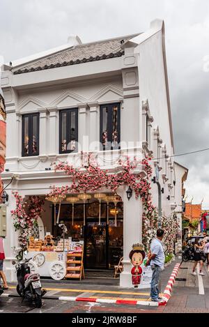 Phuket, Thailand - Juli 2022: Weißes Gebäude mit rosa Blumen an der Thalang Road in der Altstadt von Phuket. Stockfoto