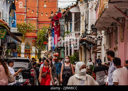 Phuket, Thailand - Juli 2022: Menschen, die entlang der Soi Rommani Street in der Altstadt von Phuket spazieren, die für ihre farbenfrohen Häuser bekannt ist. Stockfoto