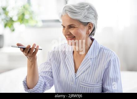 Glückliche ältere Frau, die Stimme auf dem Smartphone aufzeichnet Stockfoto