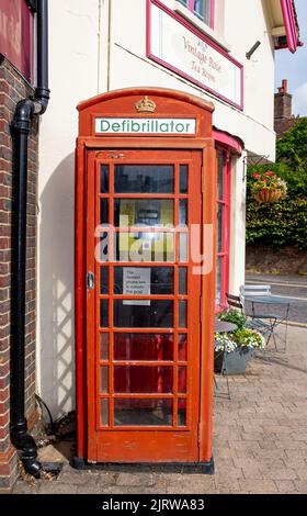 Umgebaute rote Telefonbox mit einem Herzdefibrillator-Gerät in Storrington, einer kleinen Stadt im Horsham District in West Sussex, England Stockfoto