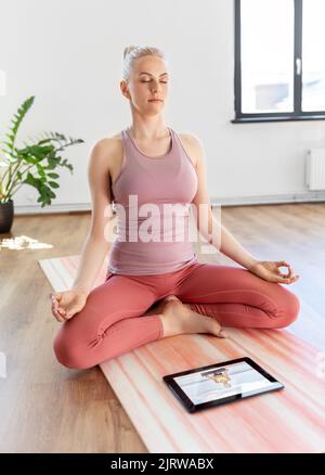 Frau mit Tablet-pc mit Online-Yoga-Kurs Stockfoto