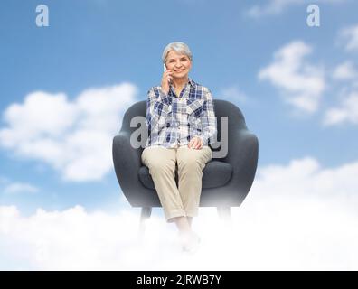 Ältere Frau ruft im Sessel auf dem Smartphone an Stockfoto