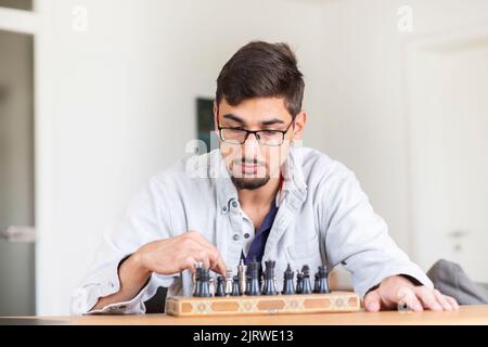 Junger Mann, der zu Hause Schach spielt Stockfoto