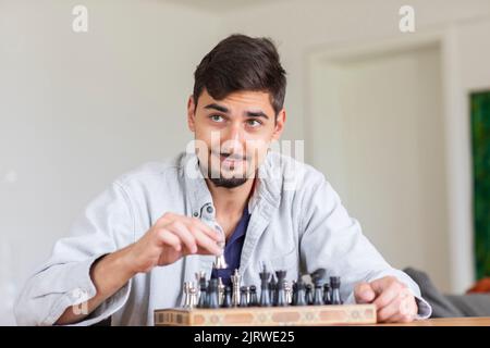 Junger Mann, der zu Hause Schach spielt Stockfoto