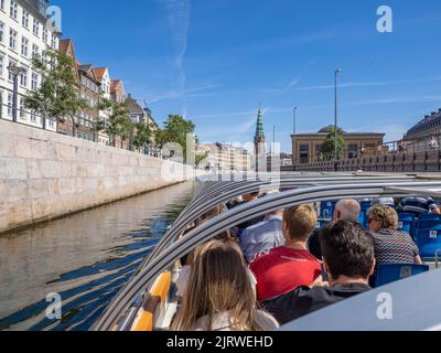 Touristen genießen eine geführte Tour durch Kopenhagen Dänemark auf einem Kanalboot, das bei strahlendem Sonnenschein entlang des Frederiksholms Kanal segelt Stockfoto
