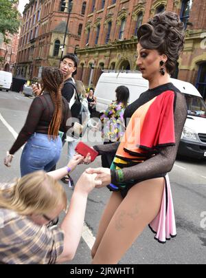 Manchester, Großbritannien. 26.. August 2022. Eine Person im Kostüm hilft jemandem aufzustehen. LGBTQ+ Pride, Manchester, Großbritannien, beginnt und geht über das Wochenende der Bankfeiertage vom 26.. Bis 29.. August in Manchesters Schwulendorf weiter. Die Organisatoren sagen: „Manchester Pride ist eine der führenden LGBTQ+-Wohltätigkeitsorganisationen Großbritanniens. Unsere Vision ist eine Welt, in der LGBTQ+-Menschen unbeschadet leben und lieben können. Wir sind Teil einer globalen Pride-Bewegung, die die Gleichberechtigung von LGBTQ+ feiert und Diskriminierung herausfordert.“ Quelle: Terry Waller/Alamy Live News Stockfoto