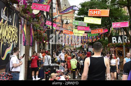 Manchester, Großbritannien. 26.. August 2022. Menschenmassen auf der Canal Street. Über der Straße hing ein Pronomen-Thema in kleinen Brettern. LGBTQ+ Pride, Manchester, Großbritannien, beginnt und geht über das Wochenende der Bankfeiertage vom 26.. Bis 29.. August in Manchesters Schwulendorf weiter. Die Organisatoren sagen: „Manchester Pride ist eine der führenden LGBTQ+-Wohltätigkeitsorganisationen Großbritanniens. Unsere Vision ist eine Welt, in der LGBTQ+-Menschen unbeschadet leben und lieben können. Wir sind Teil einer globalen Pride-Bewegung, die die Gleichberechtigung von LGBTQ+ feiert und Diskriminierung herausfordert.“ Quelle: Terry Waller/Alamy Live News Stockfoto