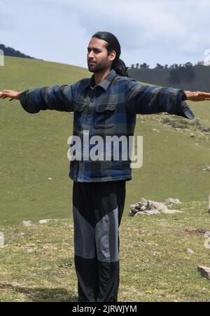 Ein gut aussehender junger Inder, der im Berg Side Arm Raise macht. Stockfoto