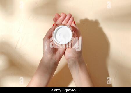 Weibliche Hände halten Glas mit Feuchtigkeitscreme Stockfoto