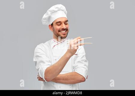 Fröhlich lächelnder männlicher Koch mit Essstäbchen Stockfoto