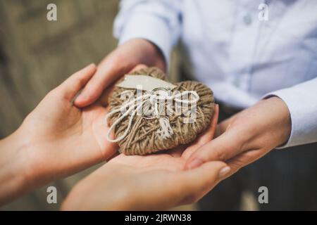 Drei Eheringe auf einem Herz aus Seilen. Stockfoto