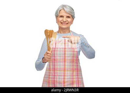 Lächelnde ältere Frau auf der Schürze mit Holzlöffeln Stockfoto